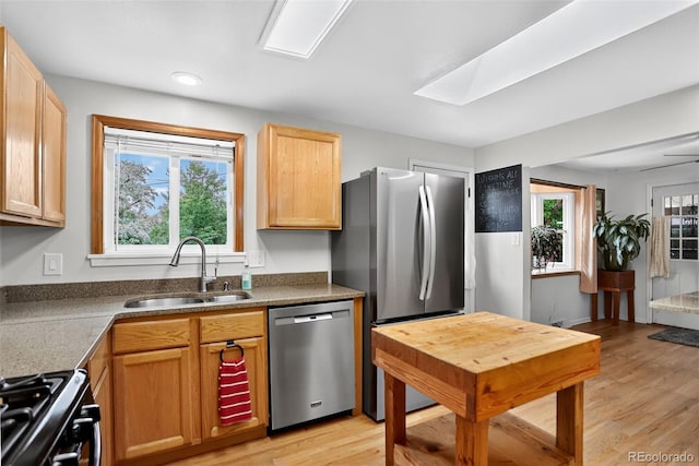 11835 W 37th Pl, Wheat Ridge, CO 80033 - kitchen featuring stainless steel appliances, light wood finished floors, light brown cabinetry, a skylight, and dark countertops