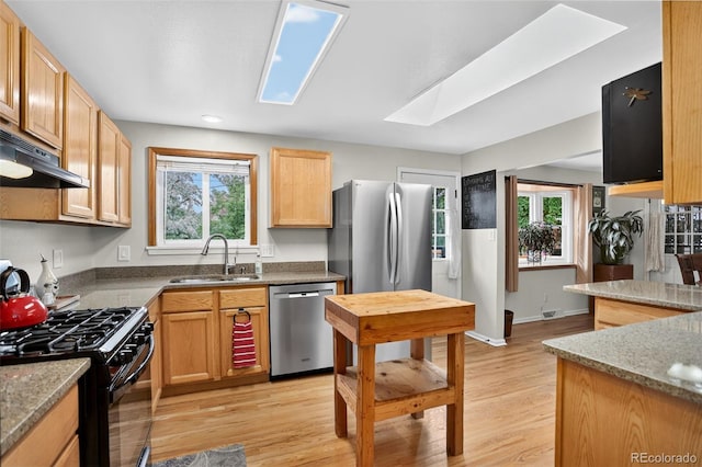 11835 W 37th Pl, Wheat Ridge, CO 80033 - kitchen with stainless steel dishwasher, black gas stove, under cabinet range hood, a skylight, and light wood finished floors