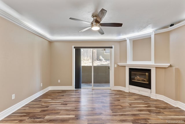 unfurnished living room with a glass covered fireplace, wood finished floors, a ceiling fan, and baseboards