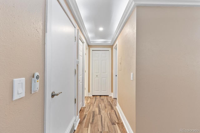 corridor with baseboards, a textured wall, and light wood-style floors