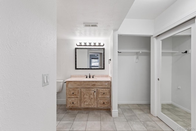 bathroom featuring baseboards, visible vents, tile patterned floors, a textured ceiling, and vanity