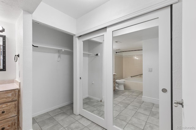 bathroom featuring tile patterned flooring, toilet, shower / bath combination, vanity, and baseboards