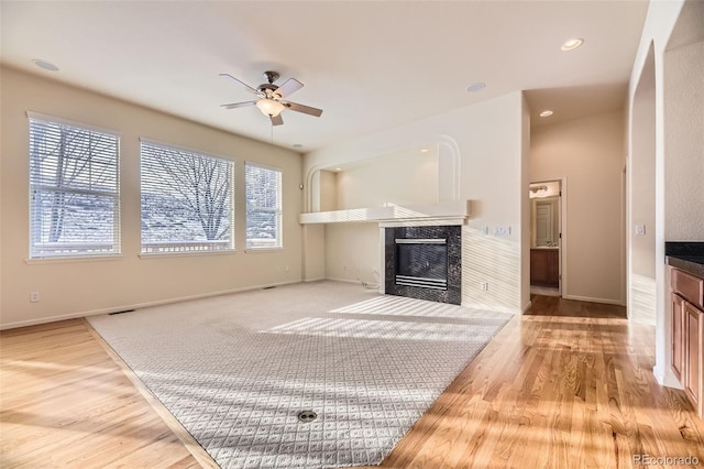 living room with ceiling fan, light wood-type flooring, and a fireplace