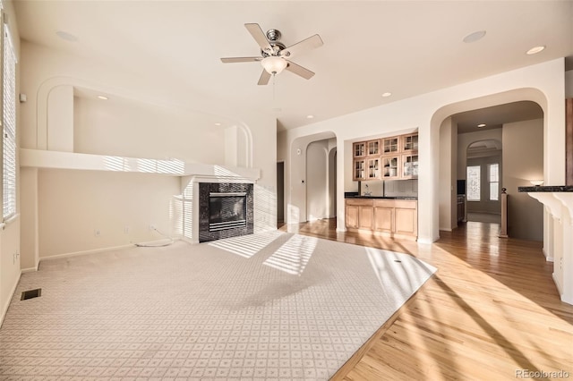 unfurnished living room featuring carpet, ceiling fan, and a fireplace