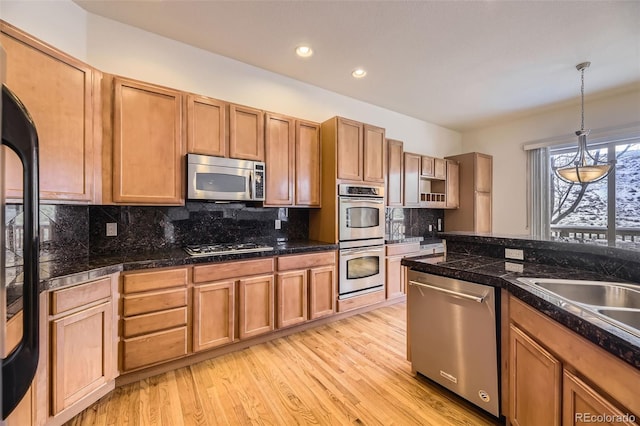 kitchen with decorative backsplash, stainless steel appliances, decorative light fixtures, and light hardwood / wood-style floors