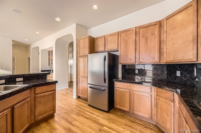 kitchen with decorative backsplash, stainless steel fridge, light hardwood / wood-style floors, and sink