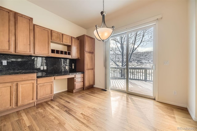 kitchen featuring decorative backsplash, pendant lighting, built in desk, and light wood-type flooring