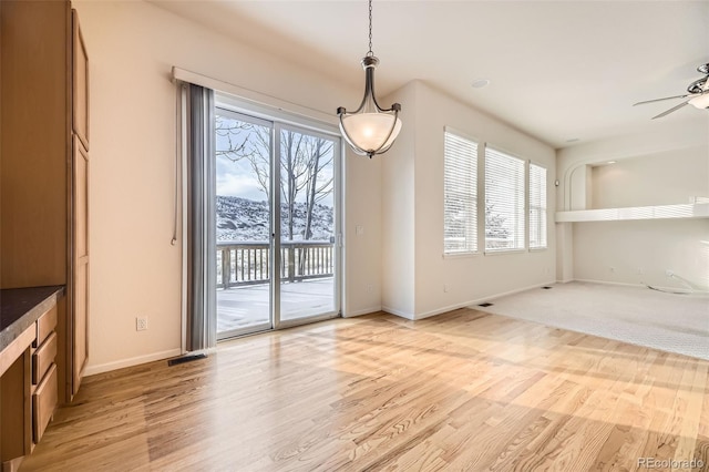 unfurnished dining area with a mountain view, light hardwood / wood-style flooring, and ceiling fan