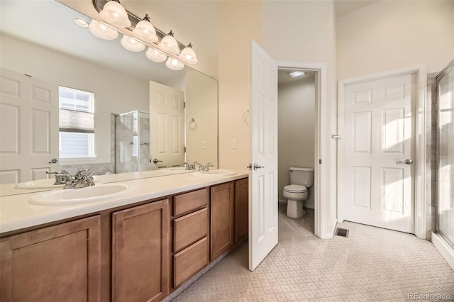 bathroom with vanity, toilet, and a shower with shower door