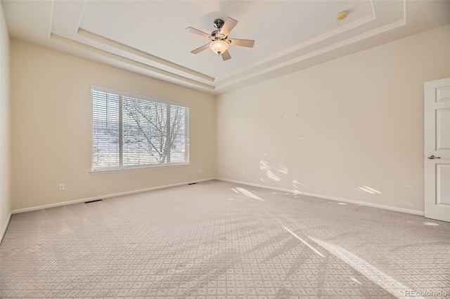 empty room with carpet flooring, a tray ceiling, and ceiling fan