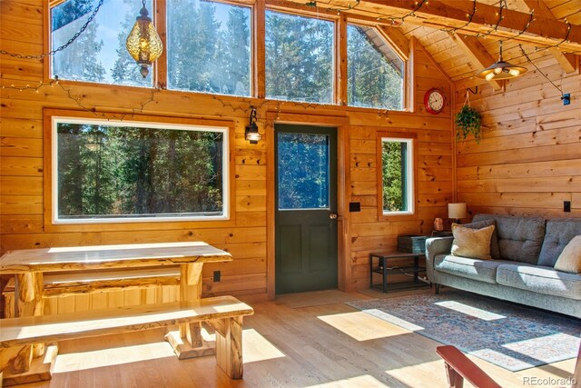 living room featuring light hardwood / wood-style flooring, wooden walls, beamed ceiling, and plenty of natural light