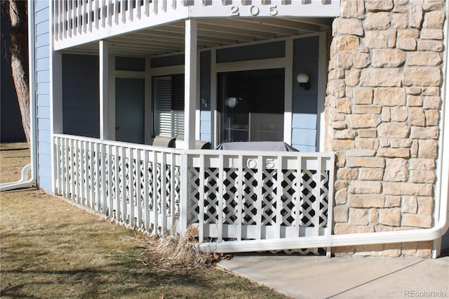 view of exterior entry featuring stone siding and a porch