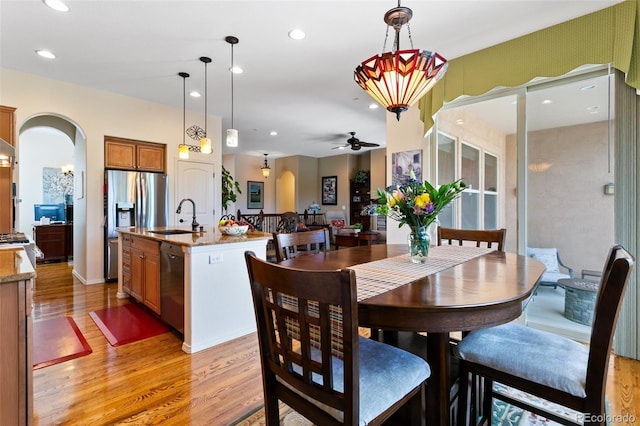 dining space featuring ceiling fan, sink, and light wood-type flooring