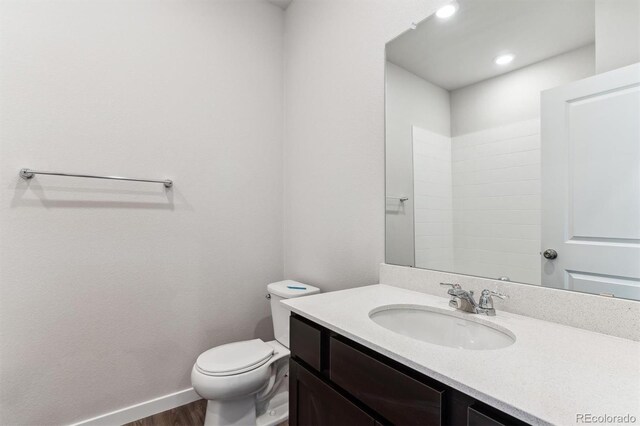 bathroom with toilet, baseboards, wood finished floors, and vanity