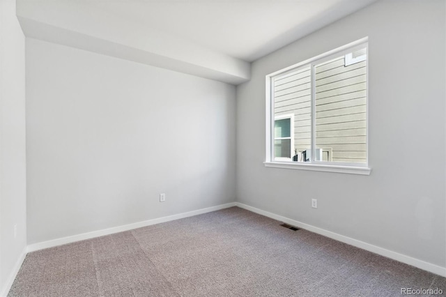 carpeted spare room featuring visible vents and baseboards