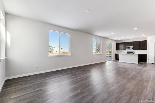 unfurnished living room featuring baseboards, dark wood finished floors, and recessed lighting