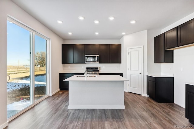 kitchen featuring dark wood-type flooring, light countertops, stainless steel microwave, and dark brown cabinetry