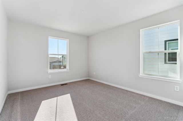 carpeted empty room with visible vents and baseboards