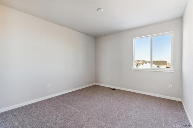 spare room with carpet, visible vents, and baseboards