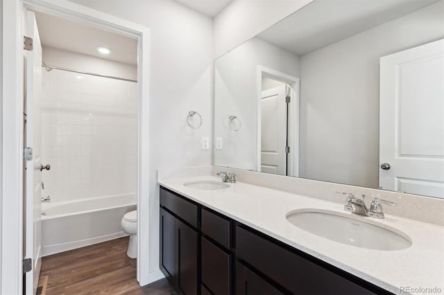 bathroom with double vanity, a sink, toilet, and wood finished floors