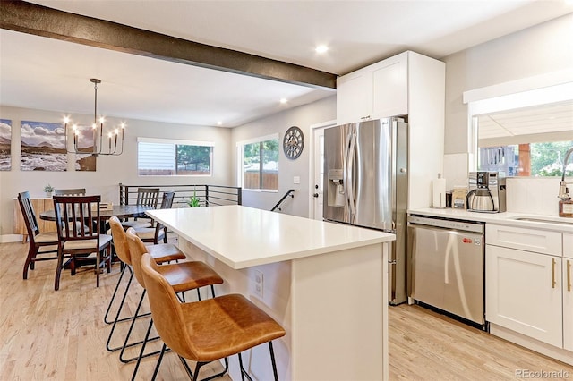 2337 S Franklin St, Denver, CO 80210 - kitchen with appliances with stainless steel finishes, a chandelier, light wood-style floors, a kitchen breakfast bar, and white cabinetry