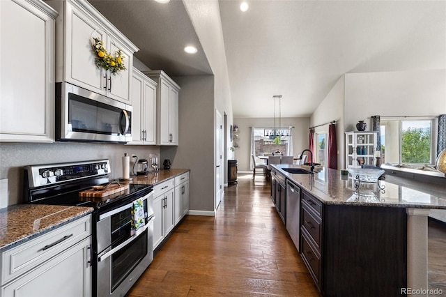 kitchen with white cabinets, stainless steel appliances, sink, an island with sink, and dark wood-type flooring