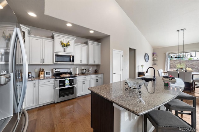 kitchen featuring dark hardwood / wood-style floors, appliances with stainless steel finishes, white cabinetry, and a kitchen island with sink