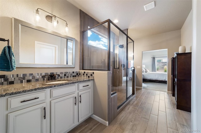 bathroom featuring walk in shower, vanity, a textured ceiling, decorative backsplash, and hardwood / wood-style flooring