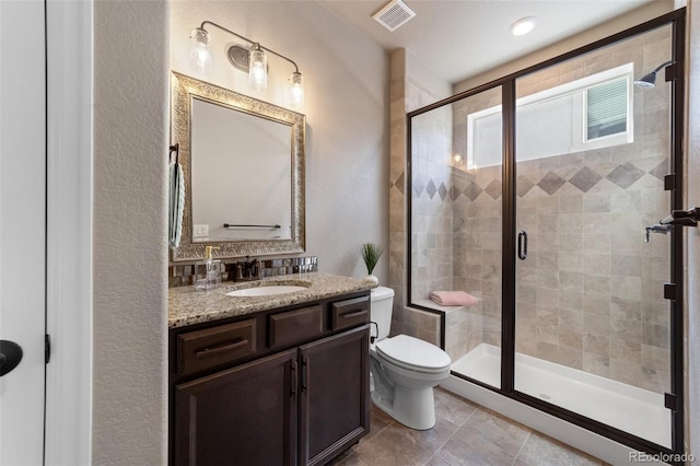 bathroom featuring tile patterned flooring, vanity, toilet, and a shower with shower door