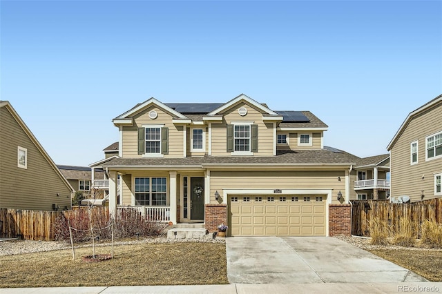 traditional home featuring brick siding, fence, driveway, and solar panels