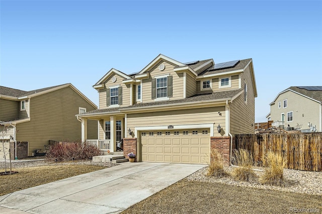 view of front of property featuring driveway, an attached garage, fence, roof mounted solar panels, and brick siding