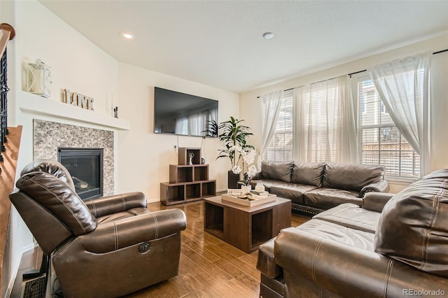 living room featuring a fireplace, baseboards, wood finished floors, and recessed lighting