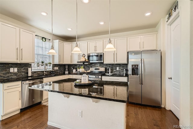 kitchen featuring decorative backsplash, white cabinets, a kitchen island, appliances with stainless steel finishes, and dark wood-type flooring