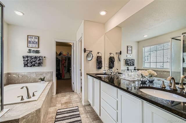 bathroom with double vanity, a garden tub, a sink, and tile patterned floors