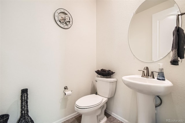 half bath with toilet, baseboards, and a sink