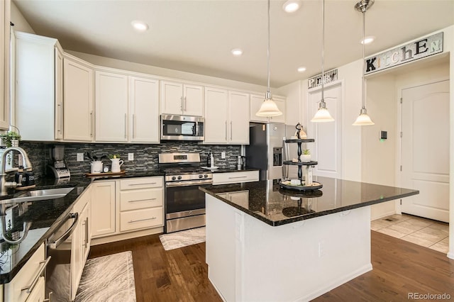 kitchen with stainless steel appliances, a kitchen island, a sink, dark wood-style floors, and tasteful backsplash