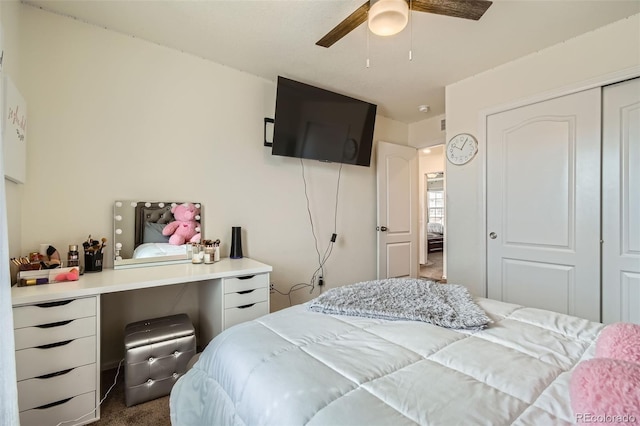 bedroom with ceiling fan, dark colored carpet, and a closet