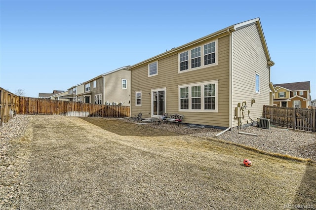 rear view of house with a fenced backyard and central AC