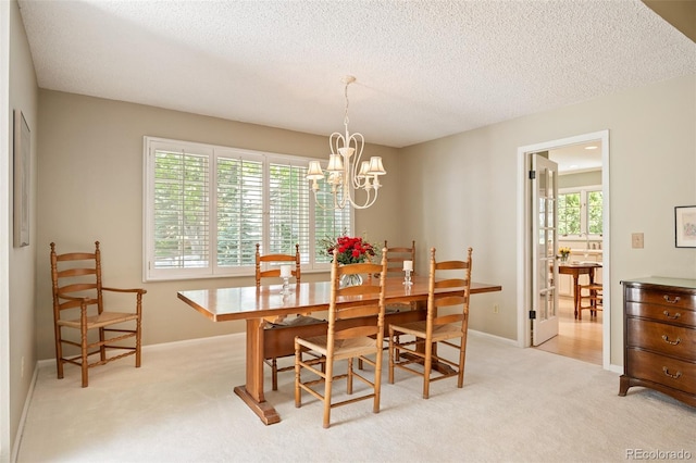 carpeted dining room featuring a notable chandelier and a textured ceiling