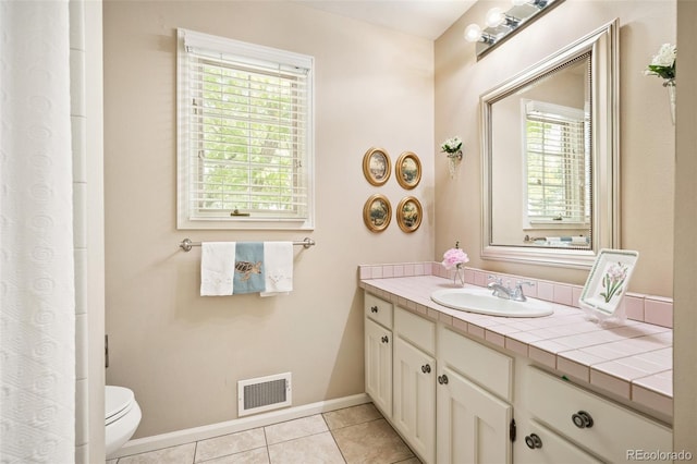 bathroom with vanity, plenty of natural light, tile patterned floors, and toilet