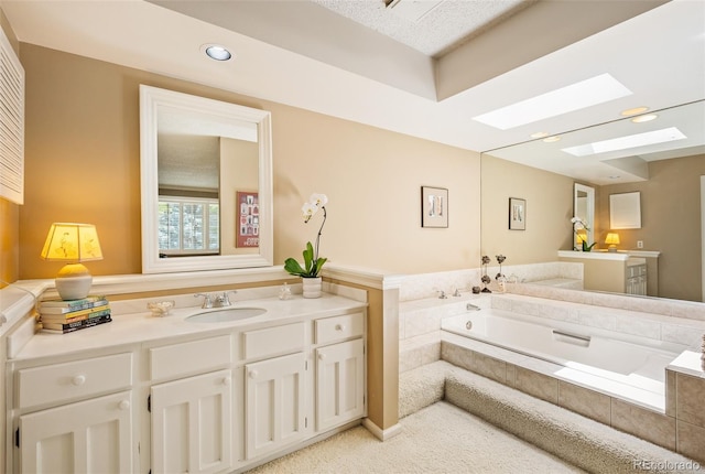 bathroom featuring vanity, a relaxing tiled tub, and a skylight