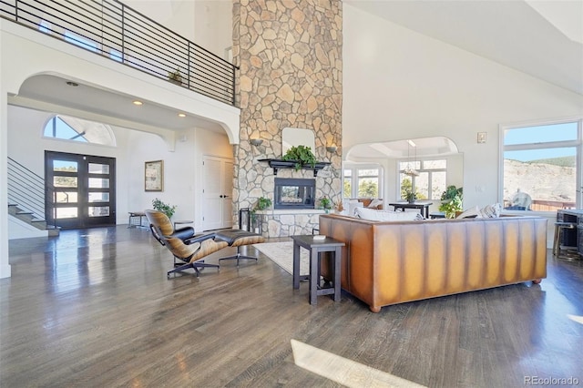 700 Apple Ridge Rd, Lyons, CO 80540 - living room featuring a towering ceiling, arched walkways, wood finished floors, a stone fireplace, and stairway