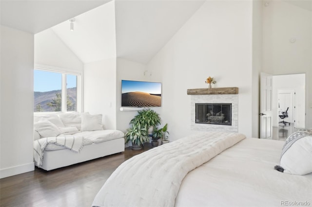 700 Apple Ridge Rd, Lyons, CO 80540 - bedroom with wood finished floors, high vaulted ceiling, a glass covered fireplace, and baseboards
