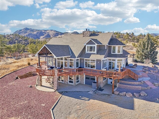 700 Apple Ridge Rd, Lyons, CO 80540 - back of house with a deck with mountain view, a patio, driveway, and stone siding