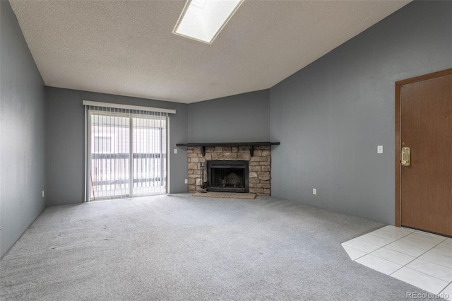 unfurnished living room with a textured ceiling, a stone fireplace, and light carpet