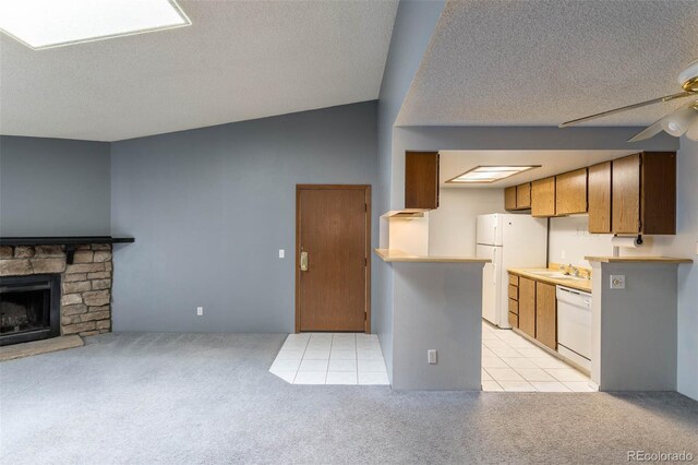 kitchen with white appliances, a stone fireplace, light carpet, lofted ceiling, and ceiling fan