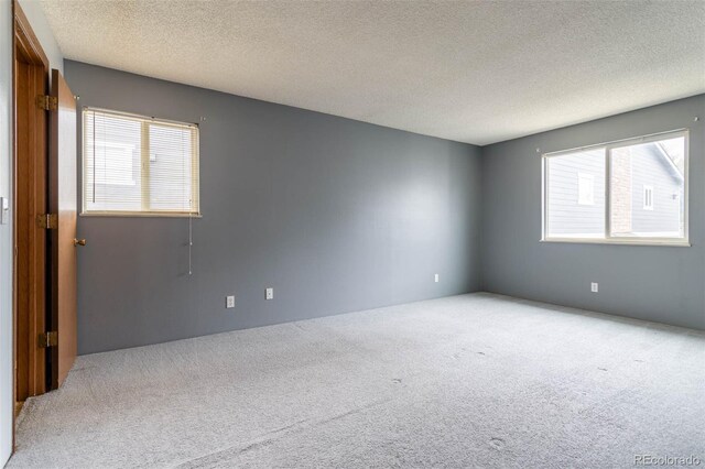 carpeted empty room with a textured ceiling