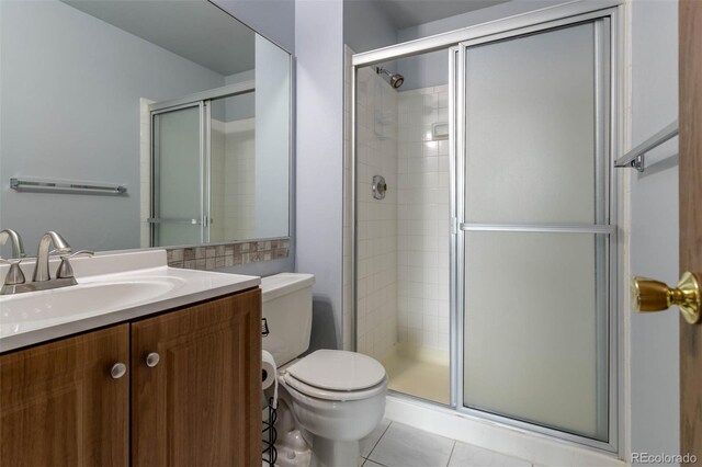 bathroom with tile patterned flooring, vanity, toilet, and an enclosed shower