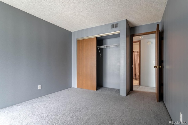 unfurnished bedroom with a closet, carpet, and a textured ceiling