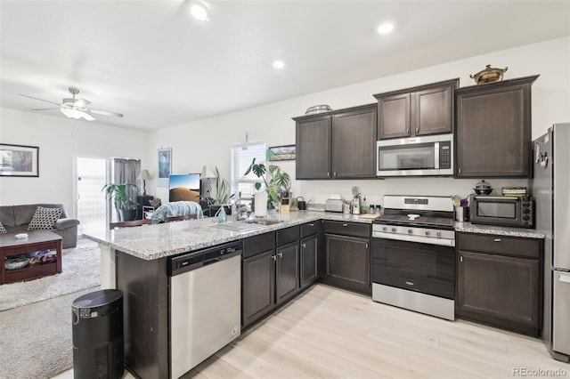 310 Quincy Rr Ave, Keenesburg, CO 80643 - kitchen with a sink, open floor plan, dark brown cabinetry, stainless steel appliances, and a peninsula